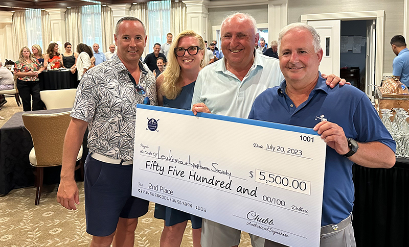 Team member holding a $5,500 check from Chubb Insurance