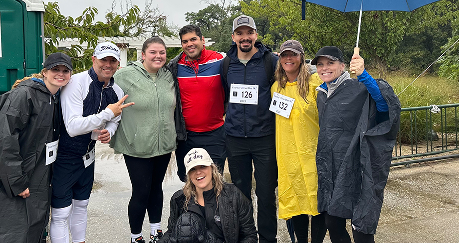 Team members participating in the Courtney's True Blue 5k run, despite the rain, to support the Courtney Lynn Blakelee Foundation. This foundation aids children affected by parental cancer, bringing joy and love into their lives. Learn more at clbfoundation.org.